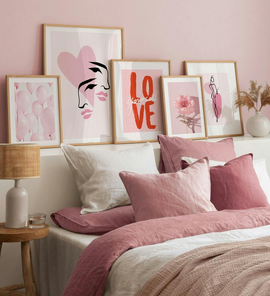 Gallery wall in pink with illustrations and photographs of flowers, line shapes and quotes with oak frames for bedroom