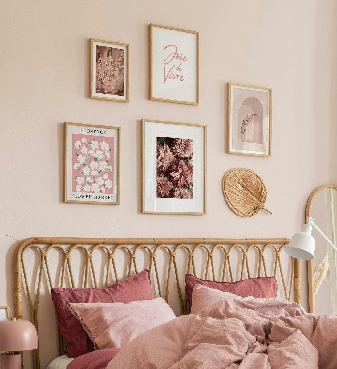 Romantic gallery wall in pink and beige with oak frames for bedroom