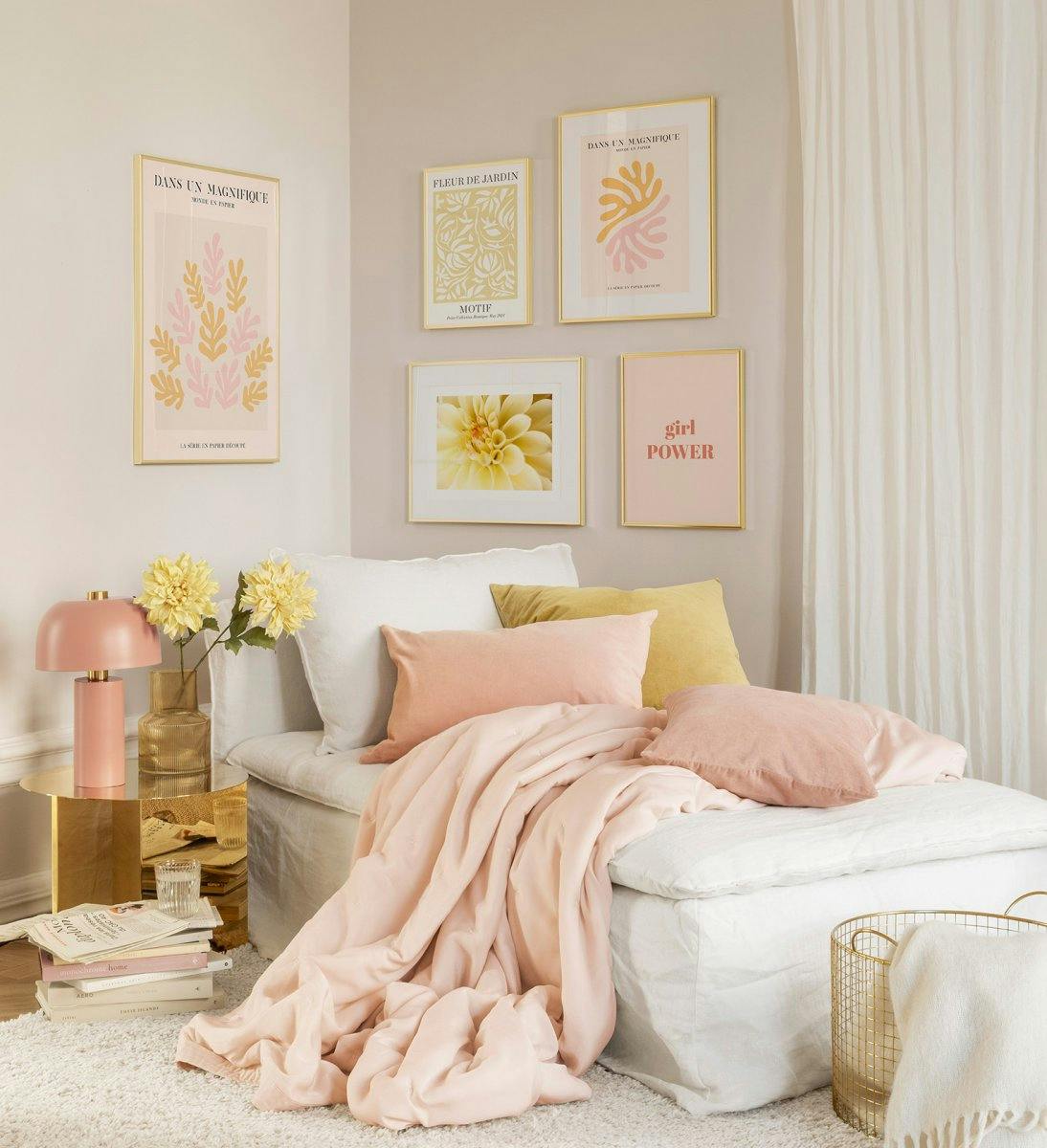 Galleria al parete alla moda con stampe in rosa e arancione e cornici dorate per camera da letto