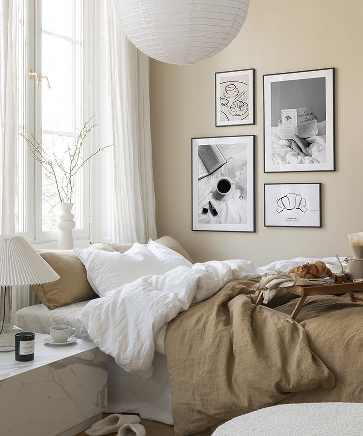 Black and white gallery wall with soft prints in black metal frames for bedroom