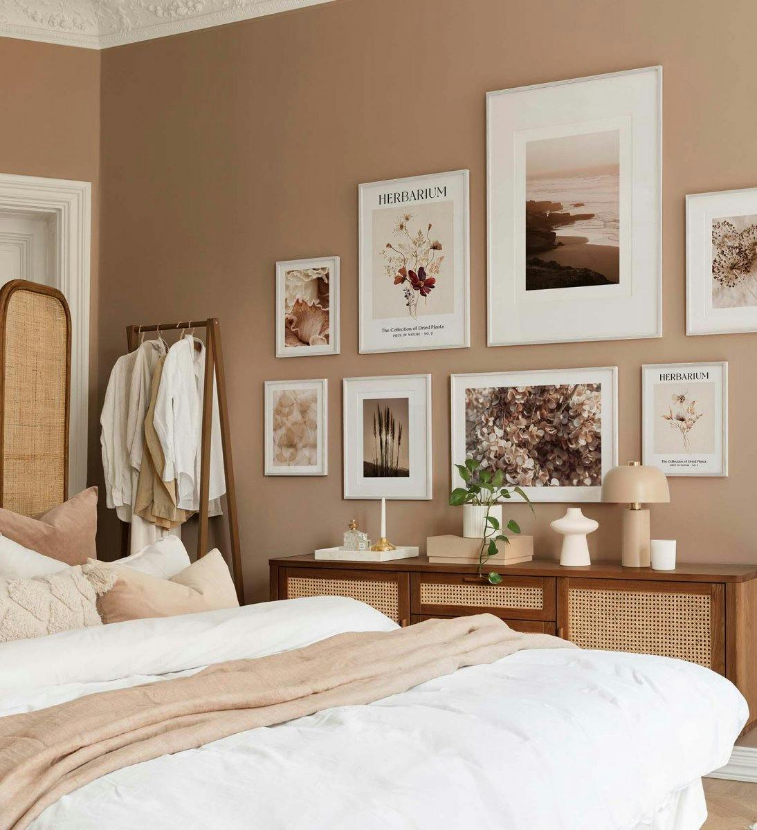 Pared de galería botánica y cercana a la naturaleza en colores marrón y beige con marcos de madera blanca para el dormitorio